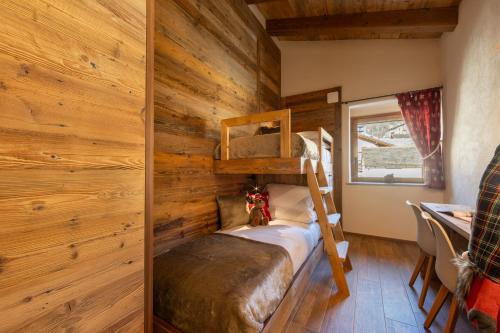 a bedroom with wooden walls and a bunk bed at Les rêves des Montagnards, Appartements de Charme in Torgnon