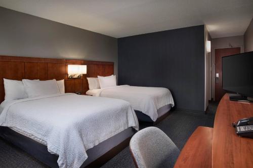 a hotel room with two beds and a television at Courtyard Winston-Salem University in Winston-Salem