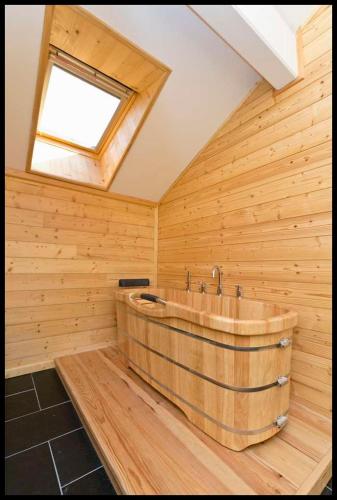 Cette chambre dispose d'une grande baignoire en bois et d'une fenêtre. dans l'établissement Etoile des neiges, à Ventron