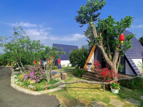 a house with a tree and flowers in front of it at Homestay Mộc Hoa Viên in Bao Loc