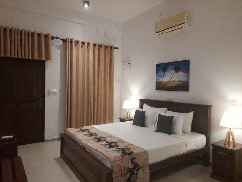 a bedroom with a bed with white sheets and pillows at Tranquil in Hikkaduwa