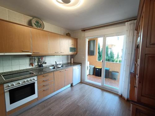 a kitchen with wooden cabinets and a large window at Chalet Estibaliz unifamiliar in Peñíscola