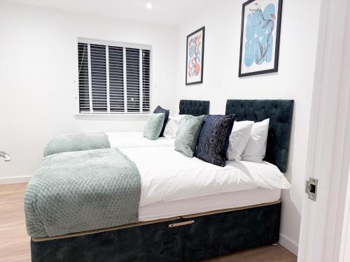a bedroom with a bed with white sheets and blue pillows at Spacious Modern 1 Bed Apartments in St Neots - Perfect for Contractors & Professionals - Free Parking - WiFi - Fully Equipped Kitchen - Smart TV Ideal for Work Stays and Long Projects in Saint Neots