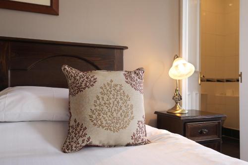 a bed with a pillow and a lamp on a table at White Lion Royal Hotel in Bala