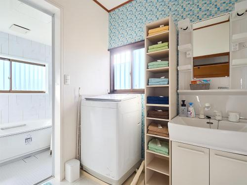 y baño con nevera blanca y lavamanos. en 九十九里PARK GARDENー寛道ー, en Ichinomiya
