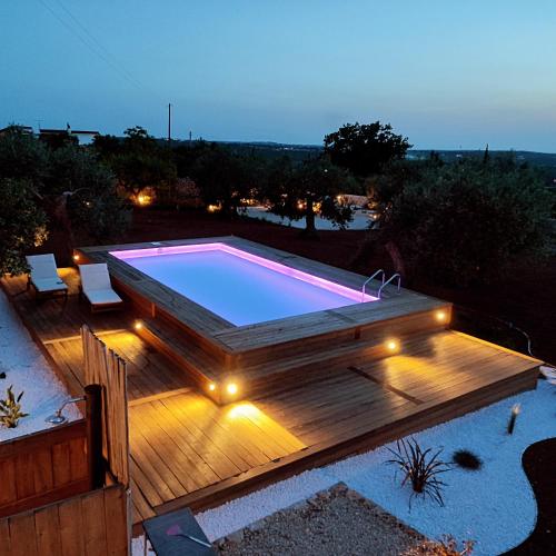 a swimming pool on a wooden deck with lights at La Relais del Trullo in Putignano