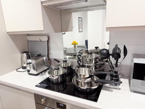 a kitchen counter with pots and pans on a stove at Spacious Modern 1 Bed Apartments in St Neots - Perfect for Contractors & Professionals - Free Parking - WiFi - Fully Equipped Kitchen - Smart TV Ideal for Work Stays and Long Projects in Saint Neots
