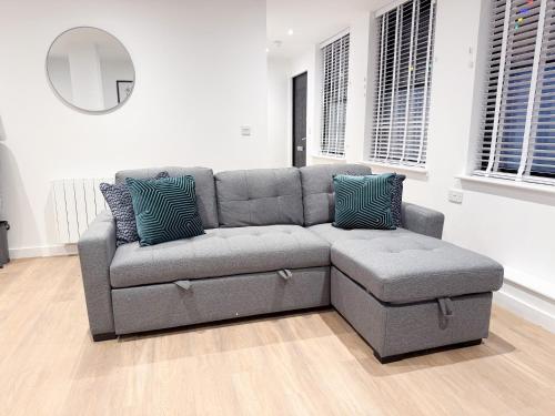 a grey couch in a living room with a mirror at Spacious Modern 1 Bed Apartments in St Neots - Perfect for Contractors & Professionals - Free Parking - WiFi - Fully Equipped Kitchen - Smart TV Ideal for Work Stays and Long Projects in Saint Neots