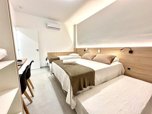 a hotel room with three beds and a desk at Ecomarine Apart-hotel 800 m Beto Carrero in Penha