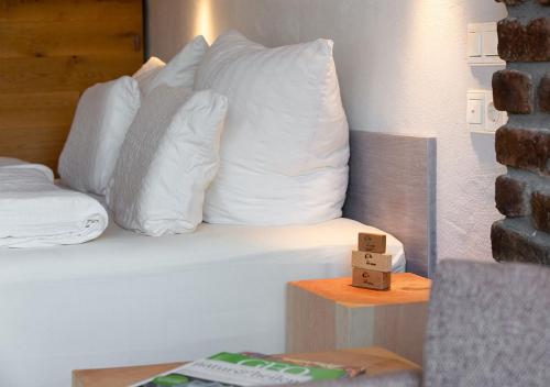 a bed with white pillows and a table with a book at Hotel Land Gut Höhne in Mettmann