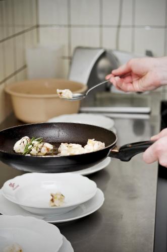 a person is cooking food in a frying pan at Gasthof & Landhotel Ohrnbachtal in Weilbach