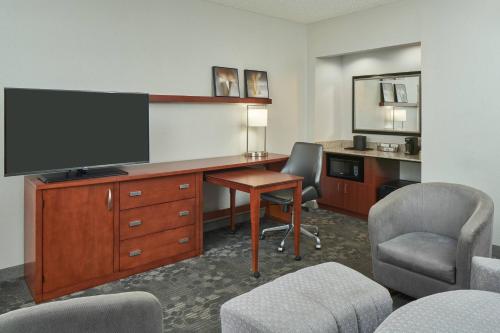 a hotel room with a desk with a television and chairs at Courtyard Chicago Wood Dale / Itasca in Wood Dale