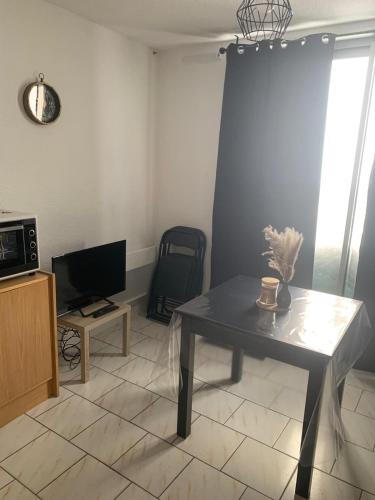 un salon avec une table et une télévision dans l'établissement Studio Club Engaly II - Valentine, à Aragnouet