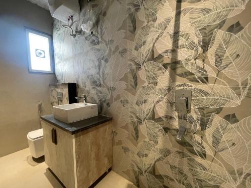 a bathroom with a toilet and a sink and a wall at Marine Ganga Stays in Rishīkesh