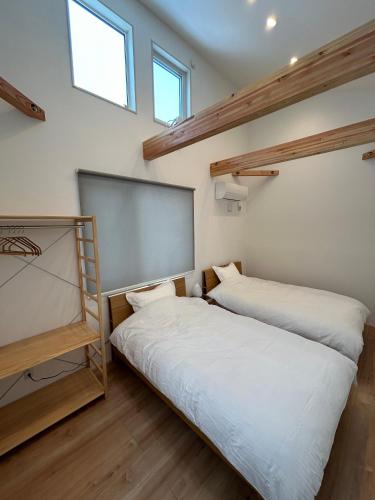 two beds in a room with two windows at Kokoro House Misorano in Hakuba