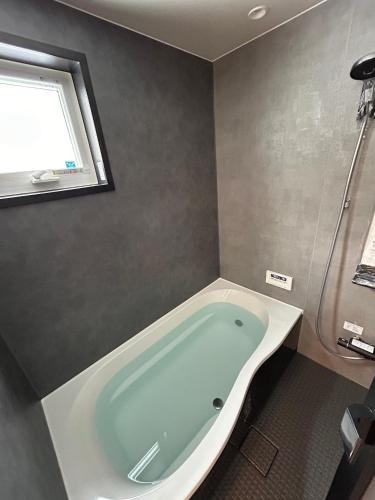 a bath tub in a bathroom with a window at Kokoro House Misorano in Hakuba