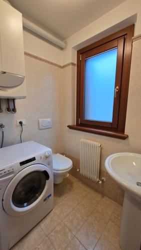 a bathroom with a washing machine and a toilet at BBkey la Villetta Garden in Arta Terme