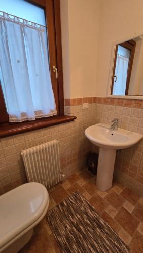 a bathroom with a sink and a toilet and a mirror at BBkey la Villetta Garden in Arta Terme