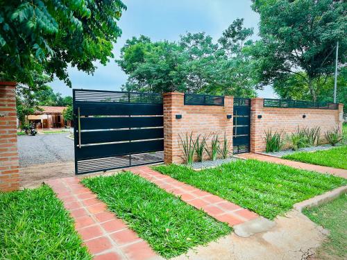 a brick fence with a black gate in a yard at Quinta Tranquilandia in Piribebuy