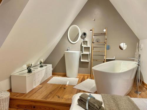 La salle de bains mansardée est pourvue d'une baignoire blanche et d'un lavabo. dans l'établissement Longère Normande, à Sainte-Marguerite
