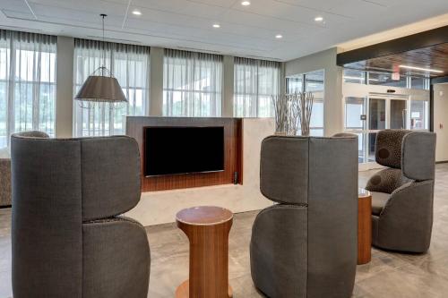 a living room with two chairs and a flat screen tv at Courtyard by Marriott Deptford in Almonesson
