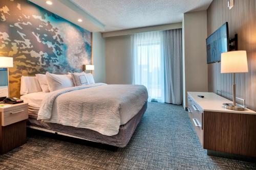 a bedroom with a large bed with a painting on the wall at Courtyard by Marriott Deptford in Almonesson