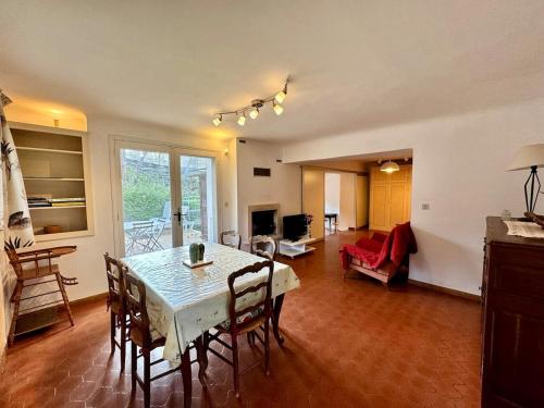 une salle à manger avec une table et des chaises et un salon dans l'établissement L'Orange, agréable gîte en pleine nature, à Hyères