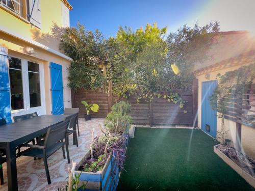 une arrière-cour avec une table et une pelouse verte dans l'établissement Maison Les Rives de la Tour Aigues-Mortes - Proche des remparts - Idéalement situé, à Aigues-Mortes