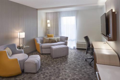 a living room with a couch chair and a television at Courtyard by Marriott Jackson in Jackson