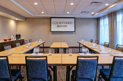 a conference room with tables and chairs and a projector at Courtyard by Marriott Jackson in Jackson
