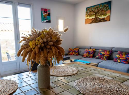 ein Wohnzimmer mit einem Sofa und einem Tisch mit einer Vase in der Unterkunft Maison Les Rives de la Tour Aigues-Mortes - Proche des remparts - Idéalement situé in Aigues-Mortes