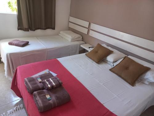 two beds in a hotel room with towels on them at AYRE GOSTOSO POUSADA in São Miguel do Gostoso