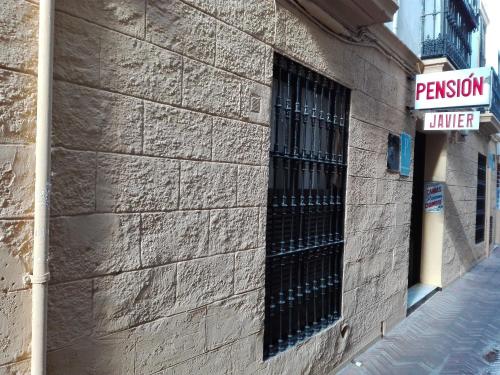 un edificio con una finestra sbarrata sul lato di Pensión Javier a Siviglia
