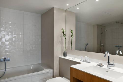 a bathroom with a tub and a toilet and a sink at AC Hotel by Marriott Innsbruck in Innsbruck