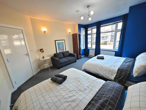 a hotel room with two beds and a couch at Bright and Spacious 2-Bedroom Flat Near Emirates Stadium in London