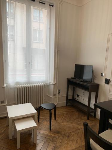 Elle comprend un salon avec une télévision, un bureau et une fenêtre. dans l'établissement Studio cœur de ville, au Mans