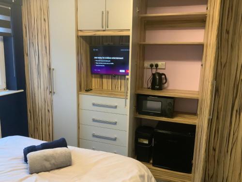 a bedroom with a bed and a tv in a cabinet at The Nest - Cosy Rooms in Harwood