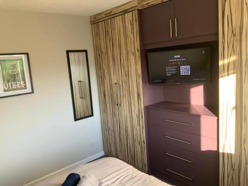 a bedroom with a dresser with a flat screen tv at The Nest - Cosy Rooms in Harwood
