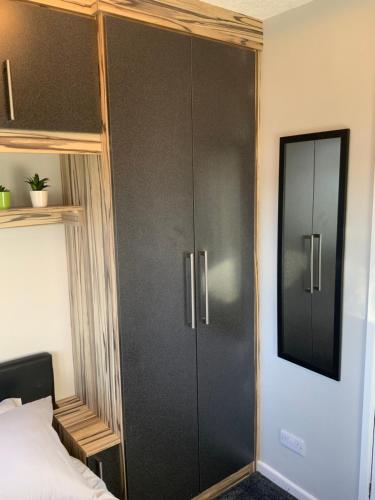 a bedroom with a large black cabinet next to a bed at The Nest - Cosy Rooms in Harwood