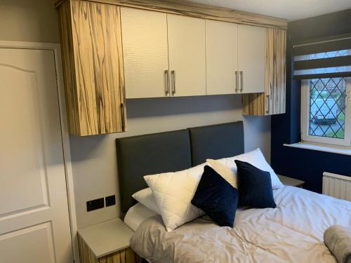 a bedroom with a bed with blue and white pillows at The Nest - Cosy Rooms in Harwood