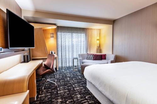 a hotel room with a bed and a flat screen tv at Courtyard Winston-Salem Downtown in Winston-Salem