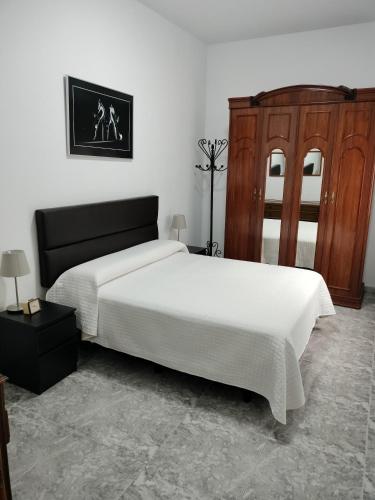 a bedroom with a large white bed and wooden cabinets at Casa Esperanza in Arinaga
