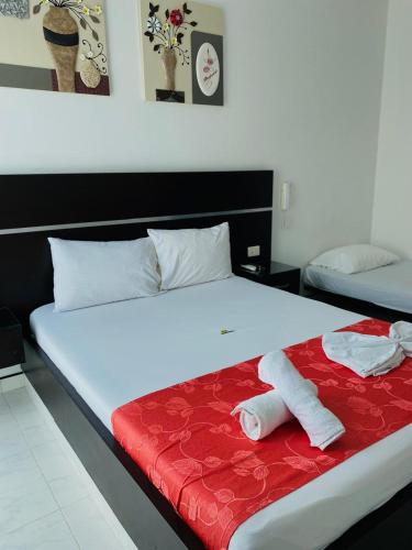 a bedroom with a bed with a red blanket at Hotel Suite Royal in Melgar