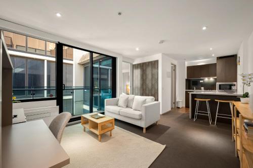 a living room with a couch and a kitchen at City Stays - Plus in Melbourne