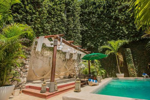 a swimming pool with a shower and an umbrella at Piedra de Agua Merida in Mérida
