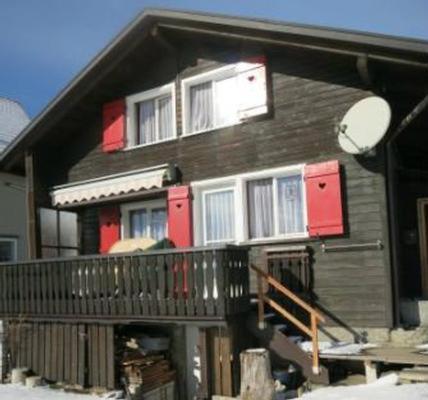 una casa di legno con porte rosse e un balcone di Ferienhaus Rheintalblick a Oberegg