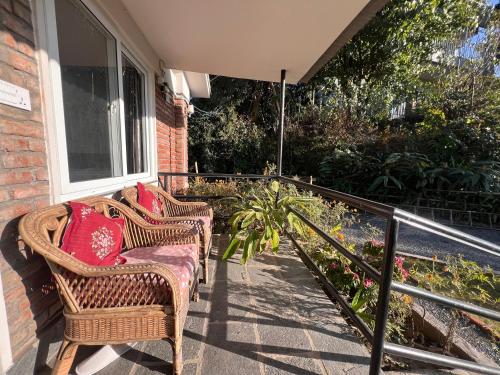 two wicker chairs sitting on the porch of a house at Avocado Accommodations in Khadkagaon