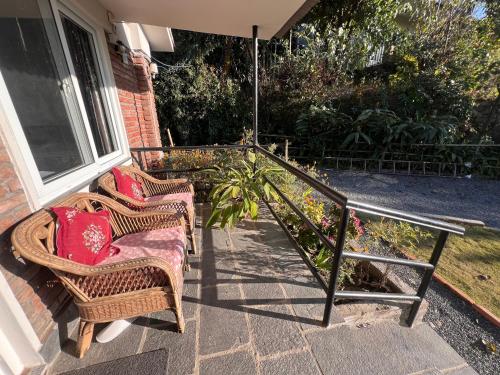 two wicker chairs and an umbrella on a porch at Avocado Accommodations in Khadkagaon