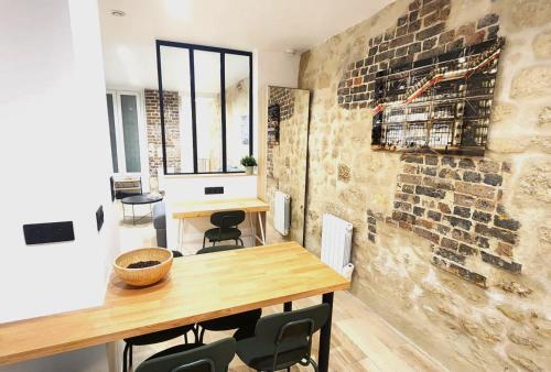 Cette chambre dispose d'une table en bois et d'un mur en briques. dans l'établissement Home in Paris Chatelet great apt for 6px, à Paris