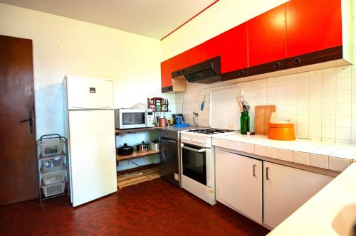 La cuisine est équipée d'un réfrigérateur blanc et de placards rouges. dans l'établissement Maison familiale tradition landaise, à Andernos-les-Bains